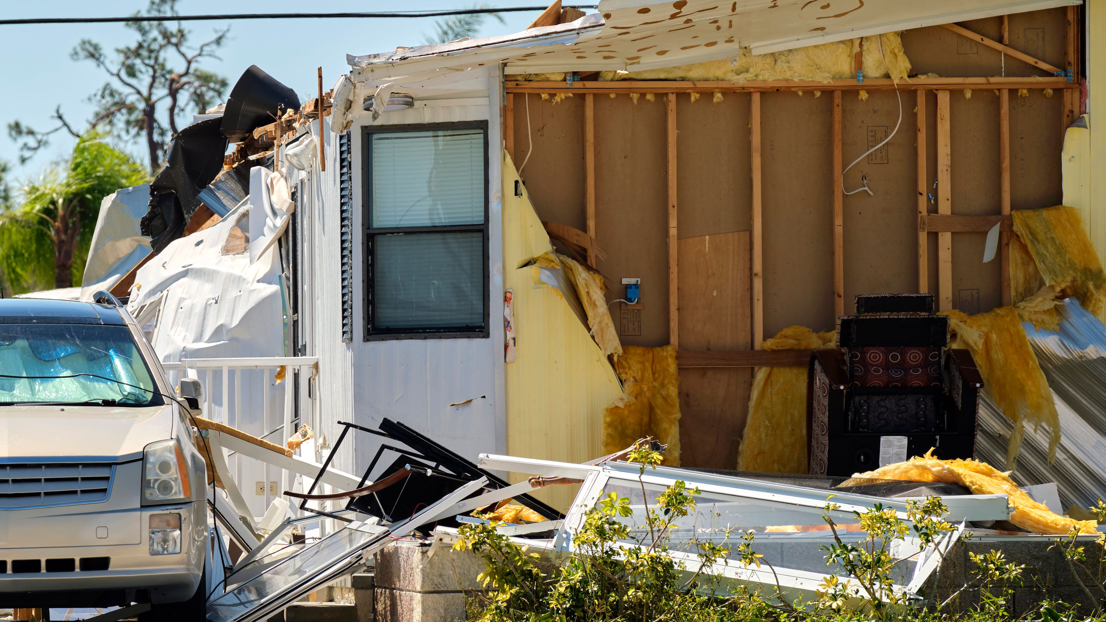 Severely damaged house and car after hurricane Ian in Florida mobile home residential area.
