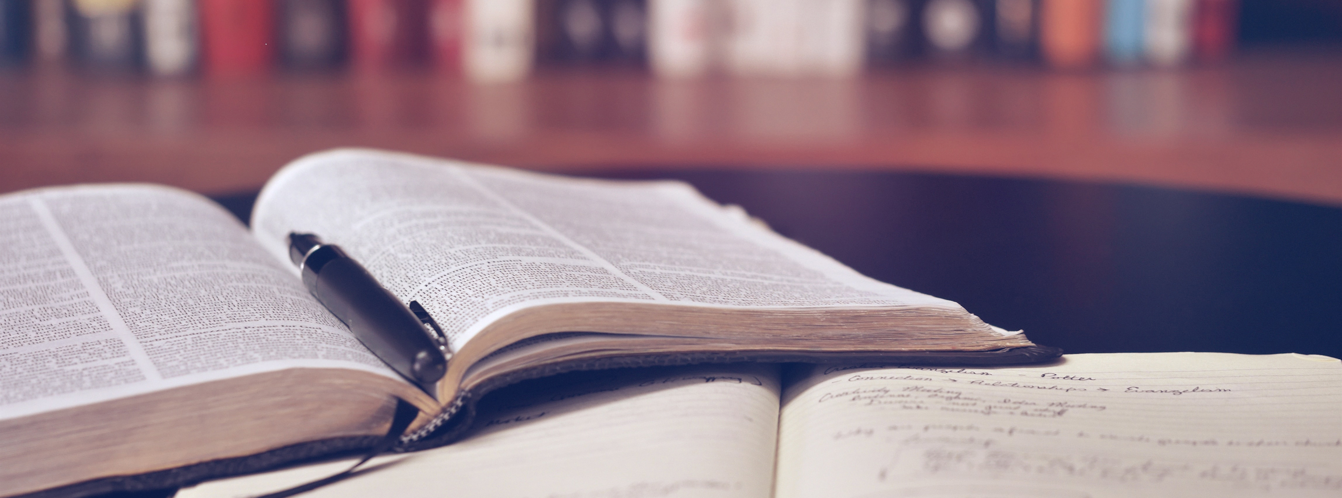 Bible and notebook sitting open on a table in an office