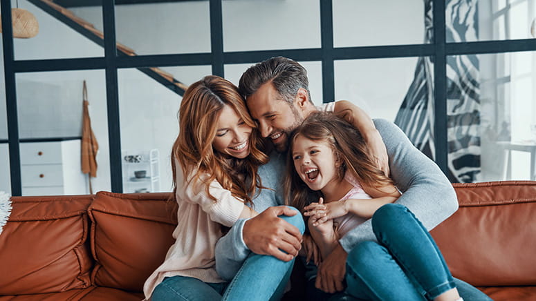 Family hugging and laughing on a couch