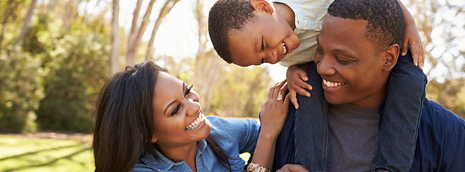 Young family having laughing with child on shoulders