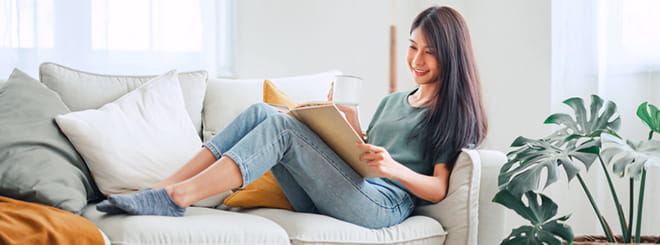 Woman looking at book sitting on a couch