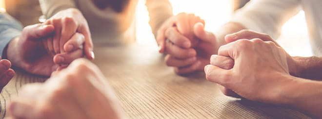 People gathered and holding hands in prayer