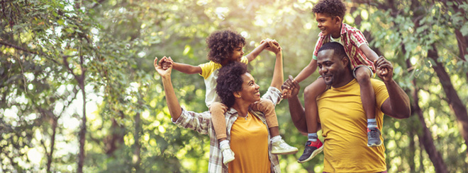 Parents with kids on their shoulders in a forest