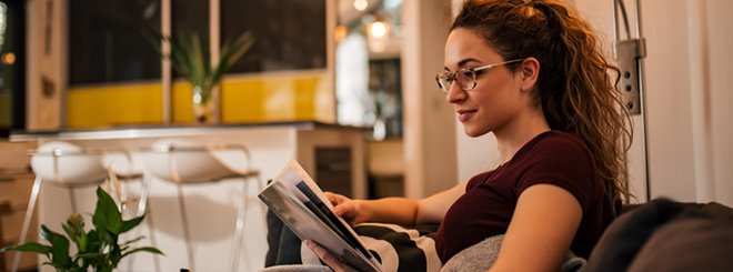 Woman looking at magazine while sitting on the couch