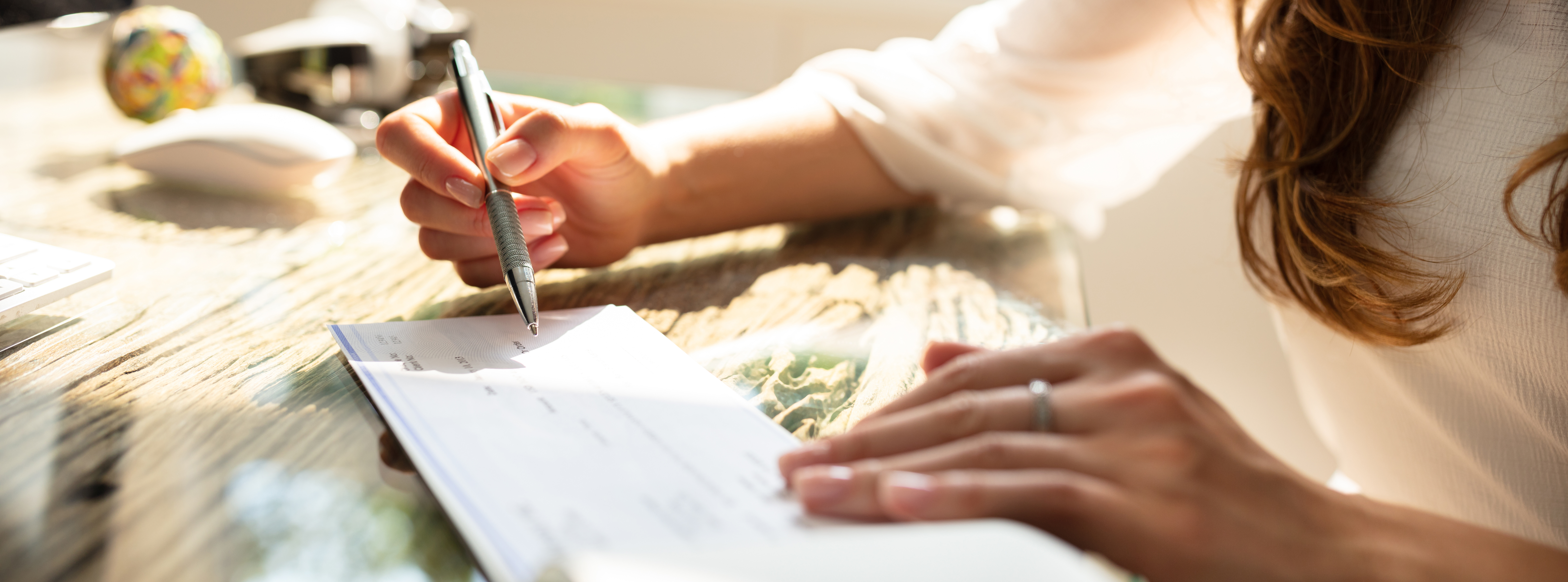 Woman signing check on a wooden desk