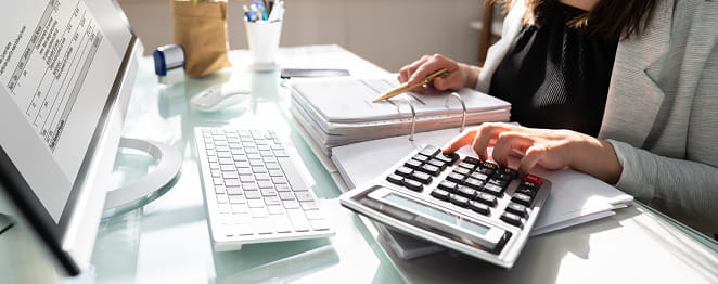 Professional woman working on a calculator and computer