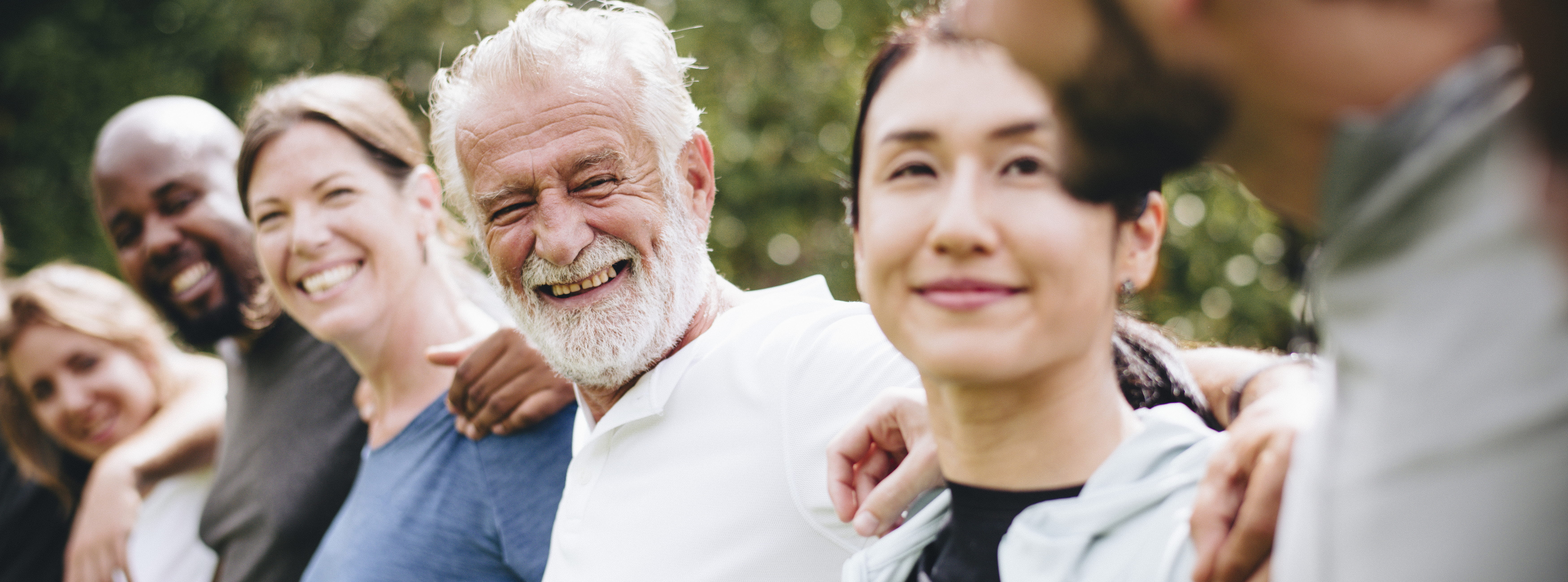 Multigenerational-multiethnic-group-with-arms-around-each-other