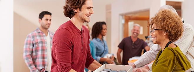 Woman handing a man a box while both volunteer