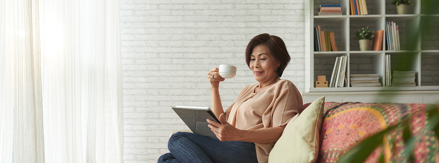 Older Asian woman sipping hot drink