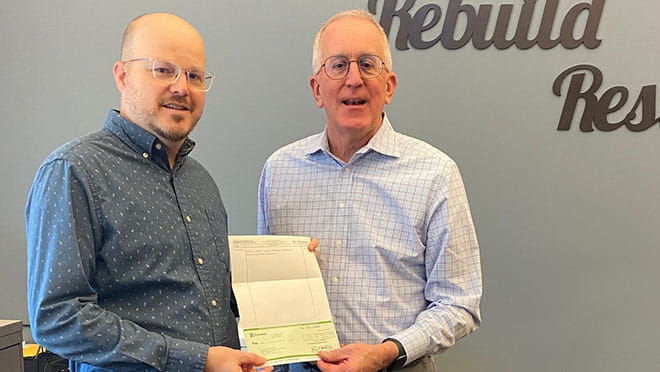 Bill Hartman (right), Everence Vice President of Organization and Fiduciary Services, presents a $50,000 donation check to Brad Fair, Development Manager at Mennonite Disaster Service. This contribution will support recovery efforts for those affected by a series of devastating hurricanes in the southeastern United States.