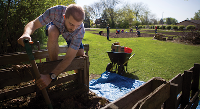 Volunteer helping shovel dirt at Jacobs garden