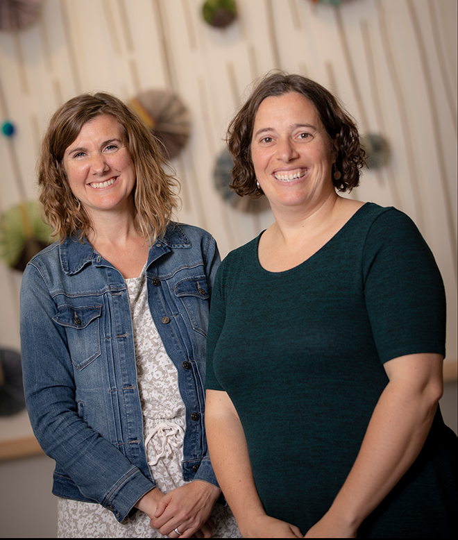 Assembly Mennonite Church pastors Anna and Lora stand next to each other smiling at camera