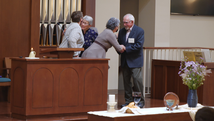 Four people at the front of a church sanctuary.