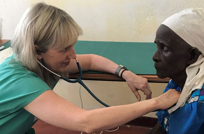 A woman uses a stethoscope to listen to another woman