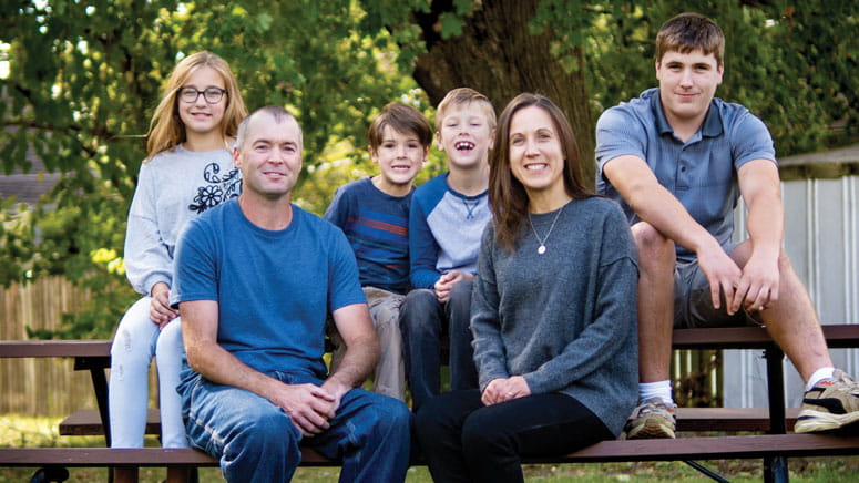 A family sitting on a picnic table, posing for a photo