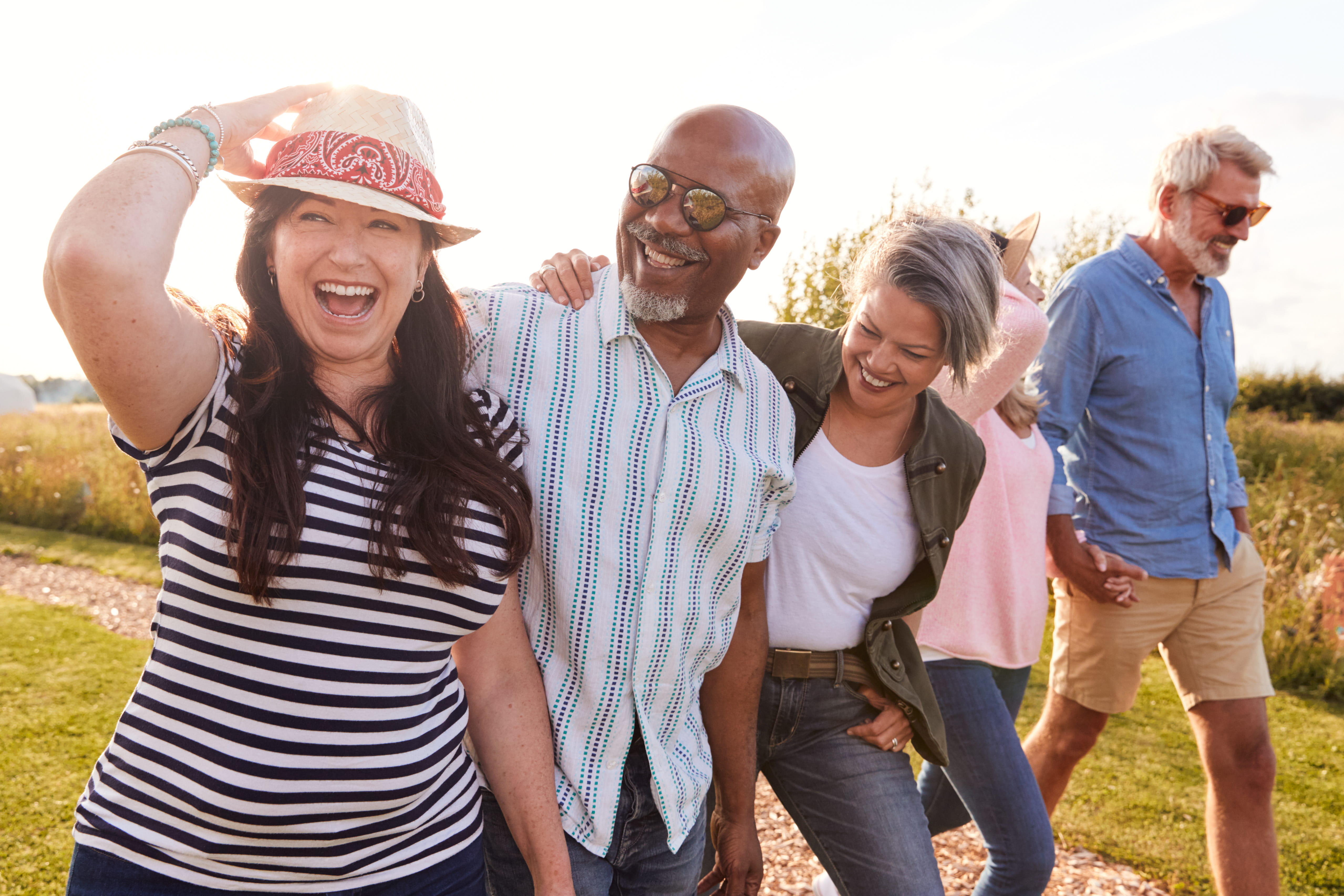 A group of multi-racial middle-aged people walk outside in golden hour light.