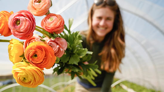 Woman holding flowers in a greenhouse