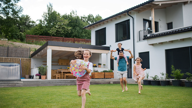 Family playing in the yard in front of a beautiful house.