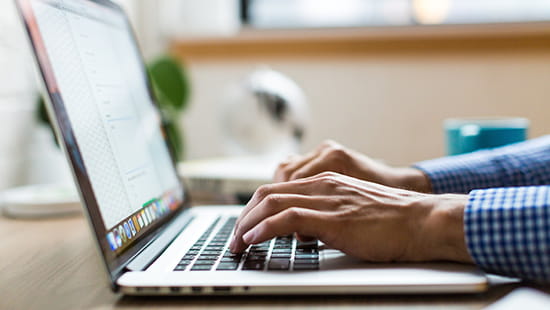 Hands typing at laptop keyboard