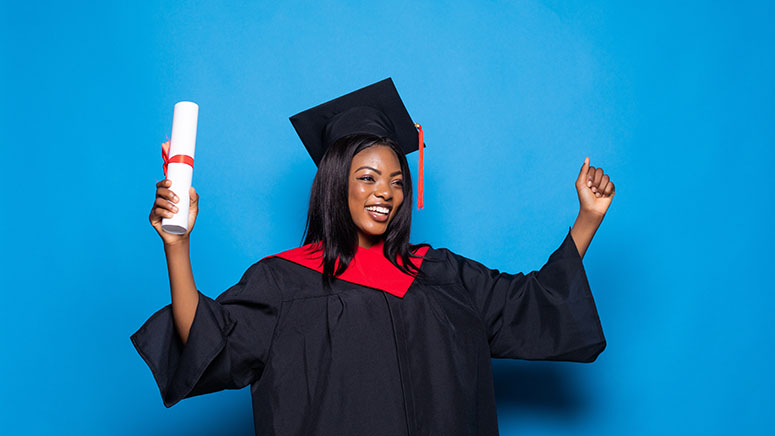 Woman dressed in graduation cap and gown holding diploma