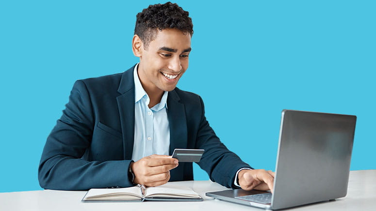 Man holding credit card and working on laptop