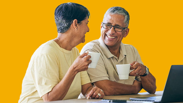 Man and woman holding coffee mugs and working on laptop