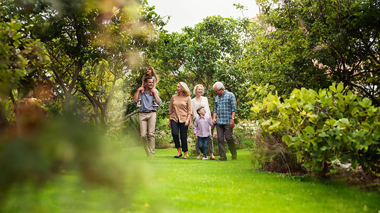 A multi-generational family walks together through a forest