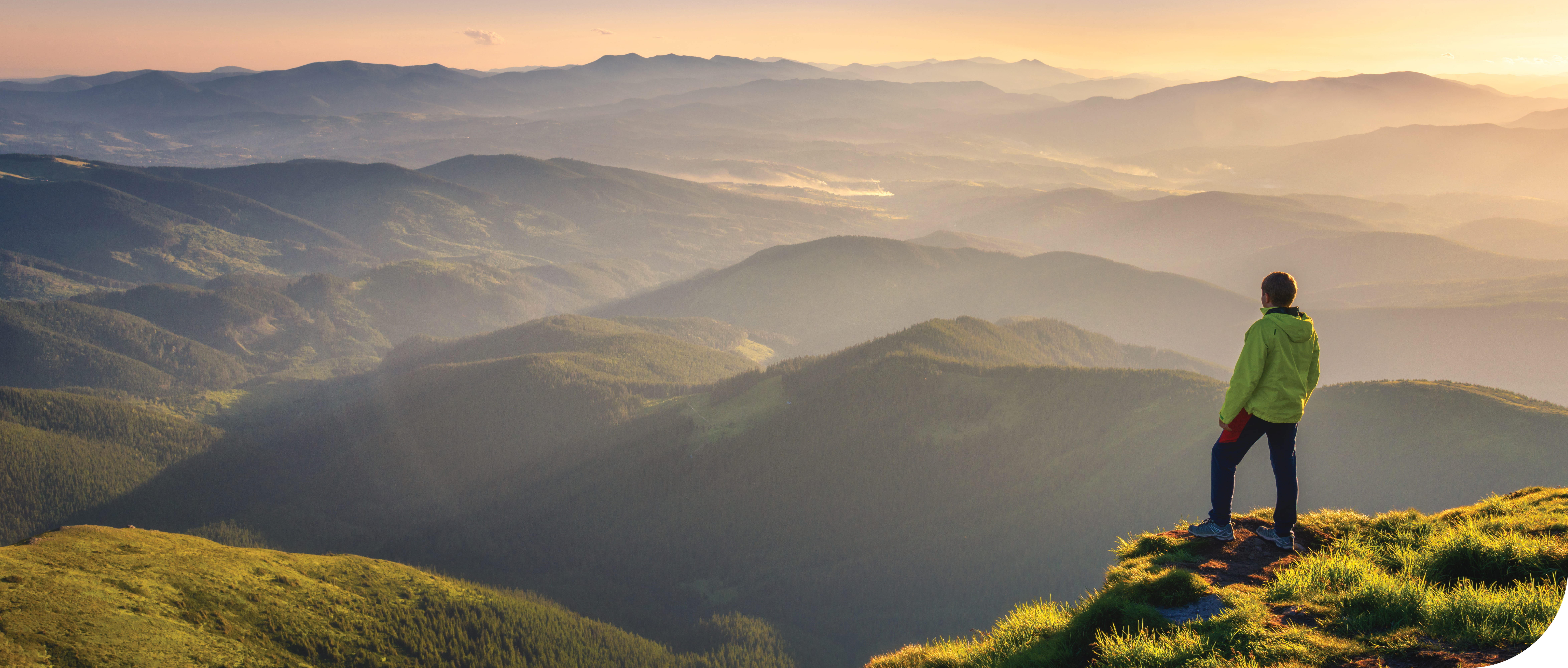 A man looks out on a beautiful scenic mountain range covered in a light fog.