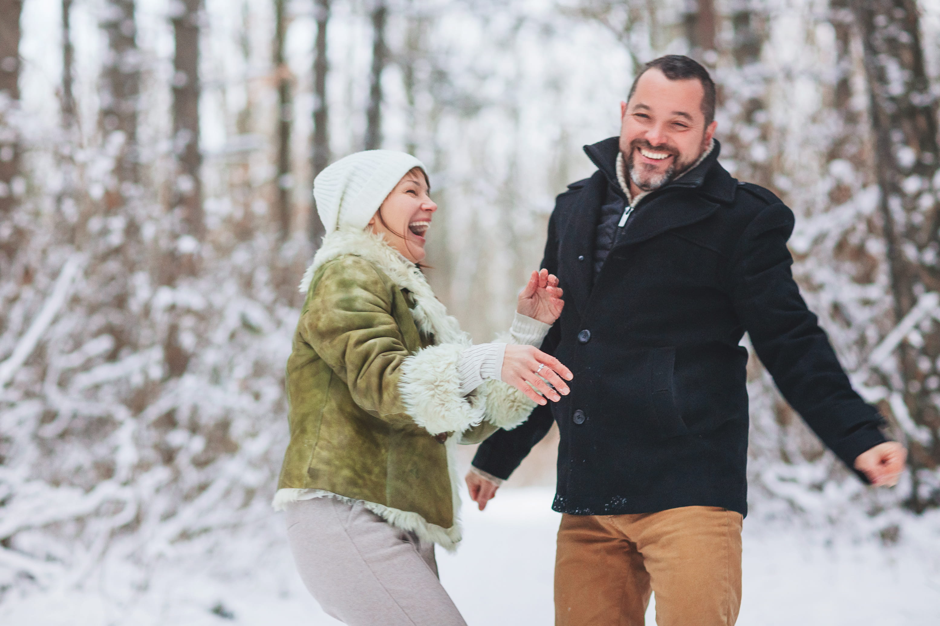 Couple laughs and plays together in the snow.