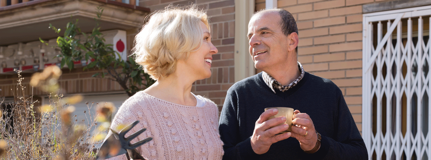 Mature couple drinking coffee outside their house on a fall morning 