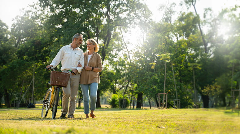 Middle-age couple walking in a park with a bicycle