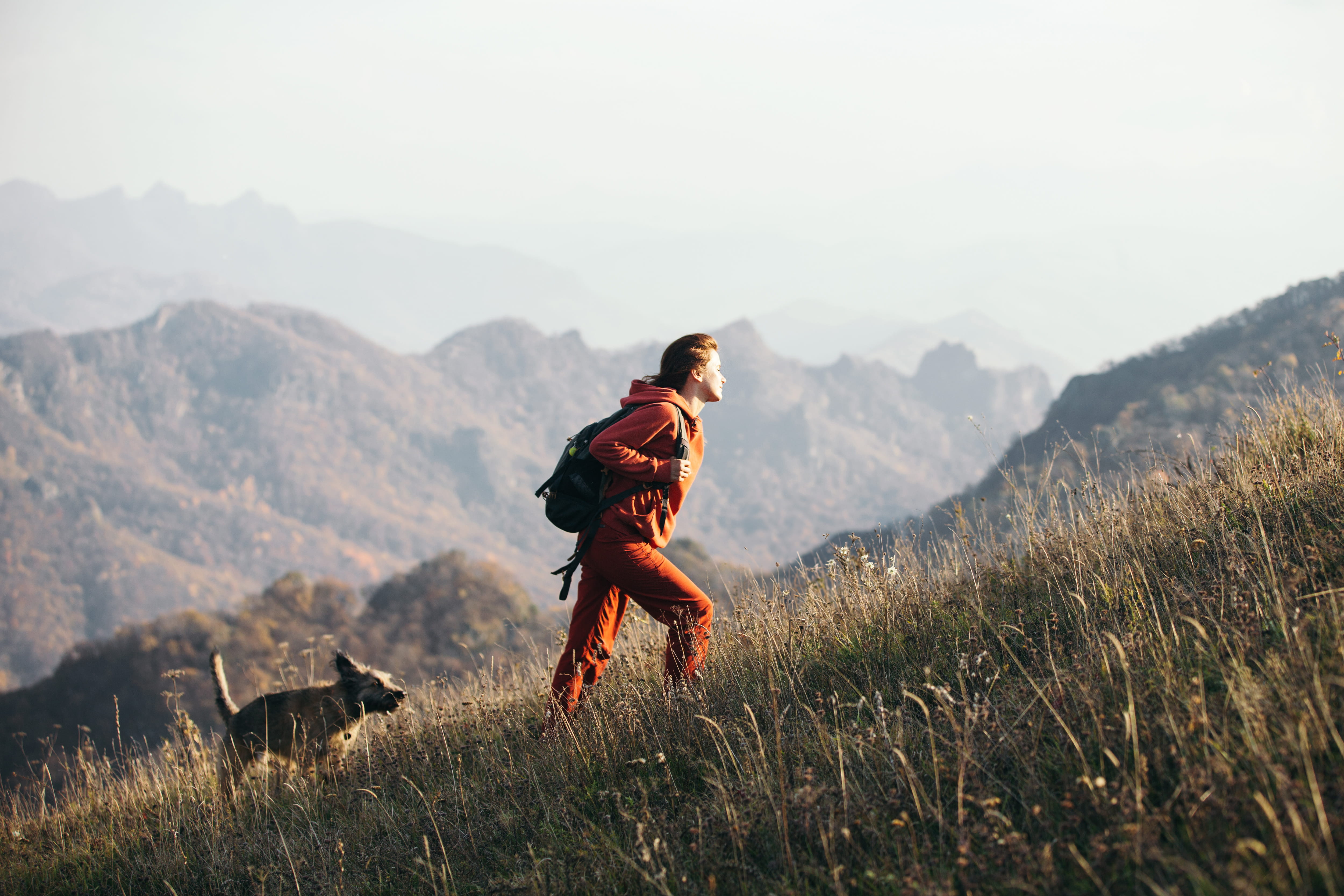 Female hiking up a hill with her dog.