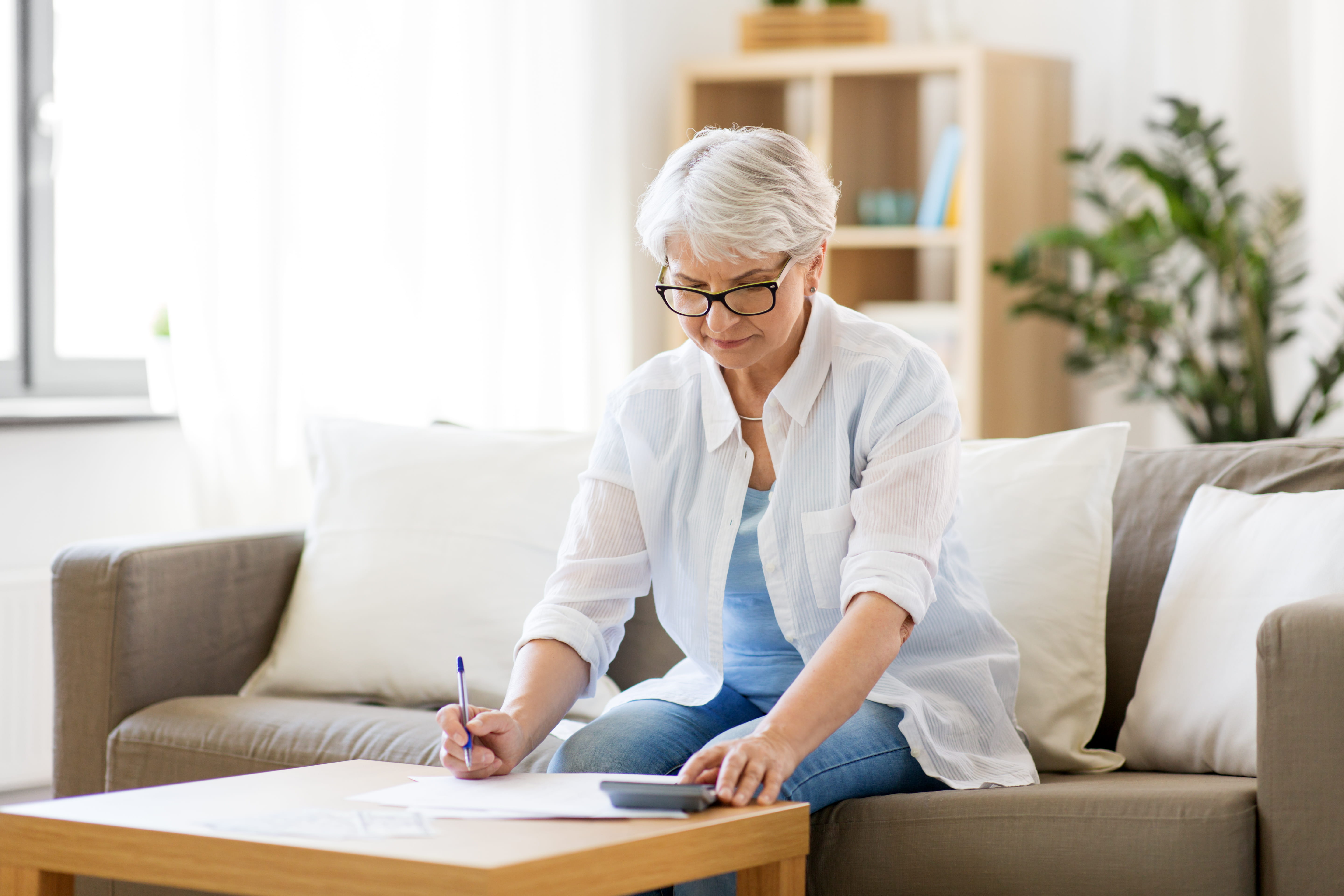 Retirement age woman doing paperwork in a living room.