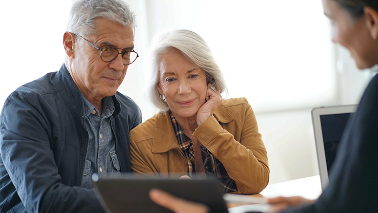 senior couple sitting together with man looking at an ipad