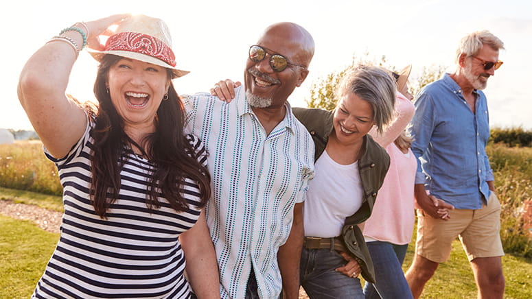 Five friends laughing walking in field