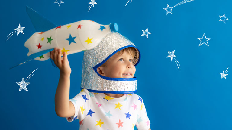 Boy dressed as astronaut playing with toy rocket